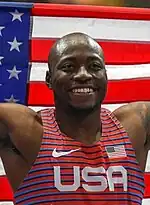 Der Weltmeister über 110 Meter Hürden Grant Holloway mit Fahne und strahlendem Gesicht