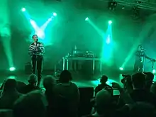Zwei Musiker und eine Musikerin geben ein Konzert auf einer Bühne.