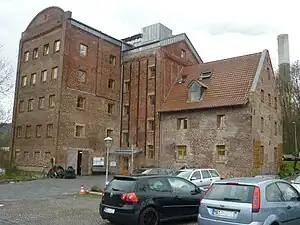 Vorderseite, links das Mühlengebäude mit Getreidesilo (Bj. 1913), rechts das ehemalige Müllerwohnhaus (Bj. 1749)