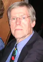 Ein Foto eines weißen Mannes gehobenen Alters, der eine Brille trägt.