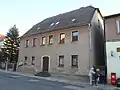 Wohnhaus und in die Tiefe des Grundstücks verlaufende Einfriedungsmauer