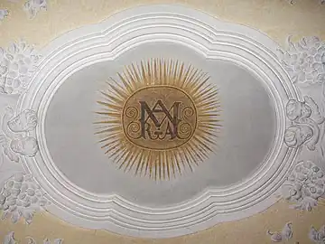 Einzig erhaltene barocke Stuckatur mit Deckenmalerei (Nordkapelle), die in einem Fresco ein Marienmonogramm zeigt.