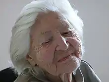 Irma Trksaks Porträt nimmt das ganze Bild ein, sie hat kurzes weißes Haar und schaut nach unten.