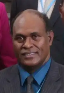 John Maneniaru anlässlich einer Delegation in Taipei, Taiwan, 26. September 2017. Porträt eines dunkelhäutigen Polynesiers im dunklen Anzug mit blauem Hemd und Glatze.