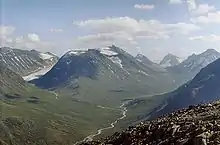 Foto einer Gebirgslandschaft und dazwischen ein Tal, durch das ein Fluss fließt