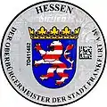 Aktuelle Zulas­sungsplakette der Stadt Frankfurt am Main mit dem hes­sischen Landeswap­pen, rechts mit DataMatrix-Code und Stadtwappen oben links