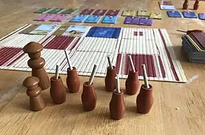 Spielmaterial von Kanagawa(Figuren und Schulbogen, im Hintergrund Karten und Diplome)