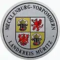Zulassungsplakette des Landkreises Müritz mit dem mecklenburg-vor­pommerschen Lan­deswappen bis 2011