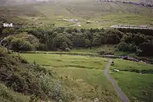 Wald am Rande von Klaksvík. Auf der Wiese die Fundamente eines ovalen Gebäudes aus der Wikingerzeit