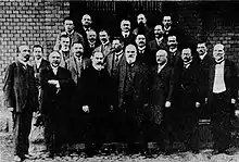 Kollegium des Wilhelmsgymnasiums in Königsberg im Jahr 1912. Professor Jäger (Jimbo), Probekandidat Unger, Professor Amoneit (Asaph), Seminarkandidat Schimanski, Professor Bork, Professor Peters, Oberlehrer Cybulla (Schybs), Professor Luther, Direktor Wagner, Vorschullehrer Braun, Professor Stange (Humpel), Oberlehrer Foethke, Professor Lullies, Oberlehrer Dehnen (Barbarossa), Professor Joost, Oberlehrer Kroll, Vorschullehrer Kirbuß, Professor Lanenpusch, Professor Kühn (Audax), Professor Kröhnert, Vorschullehrer Michaelis, Zeichenlehrer Ludat.