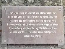 Tafelinschrift:Zur Erinnerung an Dietrich von Mandelsloh, dernach der Sage an dieser Stelle im Jahre 1385 vonMännern des Landesherrn, Herzog Heinrich vonBraunschweig und Lüneburg auf dem Wege zu einerBesprechung mit dem Herzog überfallen und er-stochen wurde, setzten ihm seine Gefolgsleutediesen Kreuzstein.