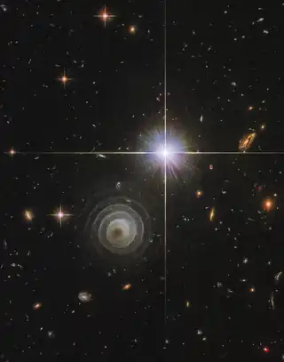 Aufnahme des Hubble-Weltraumteleskop im nahen Infrarot. Das helle Objekt rechts ist ein Stern im Vordergrund, der als Leitstern für eine spätere Untersuchung durch das größere Keck-Teleskop diente.