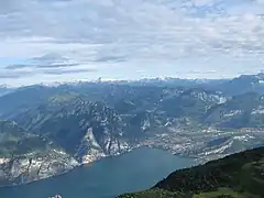 Blick vom Gipfel auf das Nordufer des Gardasees, im Hintergrund die schneebedeckten Adamello-Presanella-Alpen