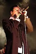 Tilo Wolff mit markant blondiertes Strähne und in ein Mikrofon singend.