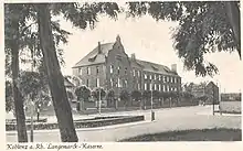 Photographie einer Photopostkarte aus dem Jahre 1910, die einen Block (Magazingebäude) des Korpsbekleidungsamts vom (später so benannten) Langemarckplatz aus zeigt (Blickrichtung: Westen). Bildunterschrift unter der Postkarte: „Koblenz a. Rh. Langemarck -Kaserne.“