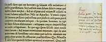 Farbfotografie von einem Ausschnitt aus einer alten Inschrift in Latein. Auf dem vergilbten Papier ist links eine Druckschrift und rechts eine handschriftliche Notiz.