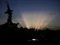 Strahlenbüschel beim Sonnenuntergang oberhalb der Wolken am Horizont.