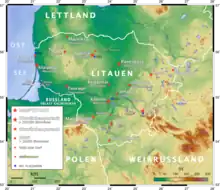 Landkarte Litauens mit farbiger Markierung topografischer Unterschiede. Hauptstadt, Distrikthauptstadt, Stadt, Wallfahrtsort und Flughafen sind eingezeichnet und in der Legende links unten erläutert.
