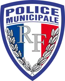 Abzeichen der Police municipale in Form eines Franzosenschildes (das heißt unten spitz zulaufend, oberer Rand leicht konvex gebogen). Der Rand ist blau, innen steht oben auf weißem Grund „Police municipale“ in serifenlosen Versalien. Die Fläche unterhalb des Schriftzugs wird nahezu vollständig von einer blau-weiß-roten Trikolore eingenommen. Auf dieser befinden sich im Zentrum die Buchstaben „RF“ in silbernen Lettern, eingerahmt von Eichenlaub am linken Rand der Trikolore und Lorbeerlaub an ihrem rechten Rand.