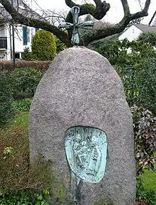Ein frei stehender Steinblock mit einem eingelassenen Relief, das im Nächsten Bild in Nahaufnahme gezeigt wird.