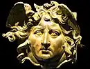 Apotropäische Verzierung (Gorgoneion) in Form eines Medusenhaupts, das am Kopfende eines Holzbalkens an der Vorderseite angebracht war