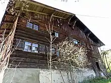 Bauernhaus, zweigeschossiger, offener Blockbau mit Flachsatteldach und profilierten Vorköpfen