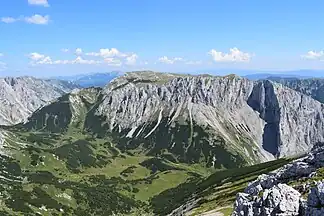 Blick vom Fölzkogel nach Osten über die Fölzalm auf die Westseite der Mitteralm. Rechts mit Schlagschatten markant vorspringend die Schartenspitze (1747 m), darüber der Kleine Winkelkogel (1918 m) unmittelbar links davon der Große Winkelkogel (1957 m). Nach links hinten steigt das Plateau zum Kampl (1990 m) an.