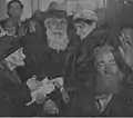 Eugénie Duchoiselle inmitten von älteren Menschen, grobkörniges Schwarzweißbild