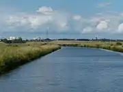 Motzener Kanal, Blick auf Straßendamm für neue B 212, Wasserturm (groß) und Kirchturm von Bremen-Blumenthal