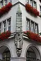 Skulptur, die das Kaufingertor auf den Schultern eines Goldschmieds darstellt