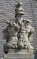 20. Trophäe – Baumstamm, Helm, Harnische, Liktorenbündel, Mörser, Kugeln.