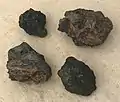 Beim Kocherursprung im Fluss gefundene schwar­ze Schlackensteine, teilweise mit rötlichen Eisenrückständen