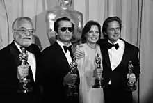 Saul Zaentz, Produzent, Jack Nicholson, Schauspieler, Louise Fletcher, Schauspielerin und Michal Douglas, Produzent halten je einen Oscar-Pokal in der Hand als Auszeichnung ihrer Leistungen für den Film Einer flog über das Kuckucksnest. Halbkörpergruppenporträt, Schwarzweißfoto, Breitformat, Vergrößerung inklusive Perforierung des Kleinbildfilms.