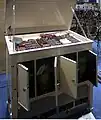 Wellenform-Scanner (unten), bestehend aus mehreren Sätzen von Kathodenstrahlröhren (CRT) und Photomultiplier-Röhren (PMT), dienen zum Abtasten der auf den Glasplatten gezeichneten Wellenformen, um Schallsignale zu erzeugen. Die Abtastgeschwindigkeit dieser Röhren wird durch ein Tonhöhenregelungssignal gesteuert.