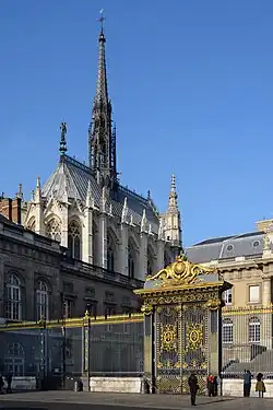 Foto des schlanken, hohen Sakralbaus von Osten auf Apsis und Nordfassade. Der untere Teil der Kapelle ist vor der Kamera verdeckt durch das davorstehendes Gebäude des Palais de Justice. Sichtbar sind die obere Hälfte der hohen Glasfenster und das Dach mit hohem Dachreiter.