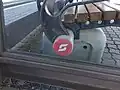 Ein weißer Pflatsch auf rotem Hintergrund, auf einer alten Bank am Saalfeldner Bahnhof, Februar 2019