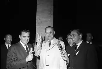 Lyndon B. Johnson zeigt Reportern das Victory-Zeichen