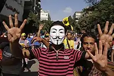 … oder als Handzeichen mit Guy-Fawkes-Maske.