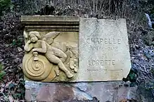Wegweiser zur Lorettokapelle Murbach mit der Spolie «Genius auf einer Schnecke»