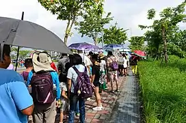 Menschen mit Sonnenschirmen in einer Warteschlange in Taiwan, 2017