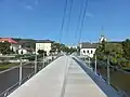 Schulgebäude und die Kirche St. Peter und Paul von der Fußgängerbrücke über Berounka