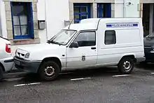 Foto eines weißen Kleintransporters vom Typ Renault Express (auf Basis des Kleinwagens Renault 5). Das Auto ist von schräg vorne aufgenommen, es steht am Straßenrand geparkt vor einem Gebäude. Auf der Fahrertür sind Name und Wappen der Stadt Pont-Aven angebracht. Am Kastenaufbau befindet sich ein blauer Schriftzug „Police municipale“ in Versalien. Die Fahrzeugvorderseite ist völlig neutral ohne Markierungen. Das Auto verfügt nicht über Blaulicht oder sonstige Kennleuchten. Sein Kennzeichen ist 7181 YH 29.