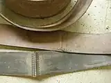 Die Lederschäftung (Klebung) von kurzen Lederstreifen, um einen sehr langen Treibriemen zu erhalten, zusätzlich mit einer Lederstreifen-Naht versehen