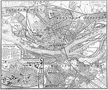 Kupferstich eines Stadtplans mit deutschen Beschriftungen. Ein Fluss namens Düna fließt durch sie hindurch. Alle Straßen, bebauten Flächen und Felder sind eingezeichnet. In der rechten oberen Legende steht der Maßstab 1 zu 70000. In der linken unteren Ecke ist von der Altstadt ein Ausschnitt mit den wichtigsten Bauten und ihrer Legende.