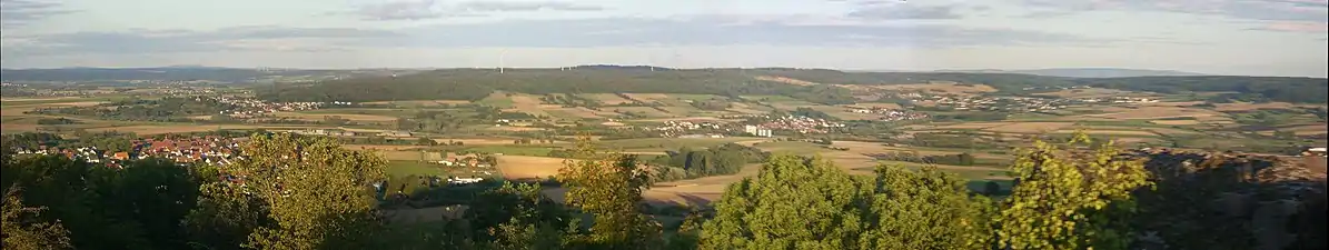 Blick vom Frauenberg auf den fast genau gleich hohen Sennberg-Rücken (bis 383 m). Mittig lugen die mit 405,1 m und 406,8 m nur minimal höheren Gipfel der Mardorfer Kuppe (etwas dunkler) hervor. Links im fernen Hintergrund der 592 m hohe Rimberg, rechts in ebendem der Hohe Vogelsberg (bis 773 m).