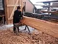 Ein Stamm wird mit dem Breitbeil zugerichtet