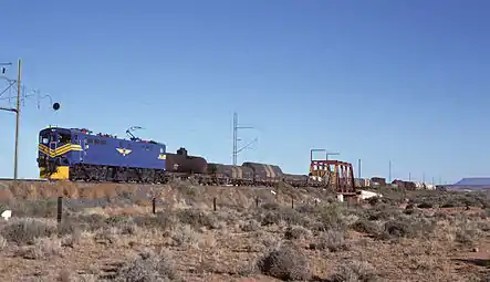E7008 im blauen Spezialanstrich der SAR für den Einsatz vor dem Blue Train, aber vor einem Güterzug bei Die Put, ungefähr 16 km südlich von De Aar, eingesetzt, am 2. Mai 1985