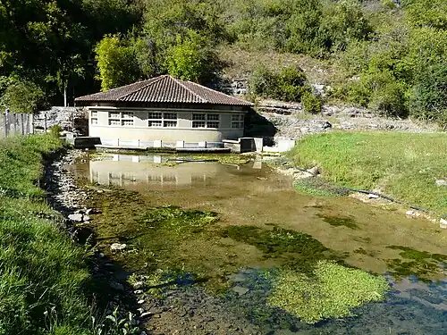 Karstquelle der Glane mit Pumpenhaus, dahinter flach nach Nordost einfallendes  Unter/Mittelbathonium