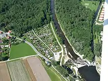 Luftbild, das das Ackermannwehr mit der Abzweigung des Fabrikkanals (rechts) von der Wertach (Bildmitte) zeigt. In der rechten oberen Ecke sieht man das Gögginger Luftbad. Norden ist oben.