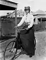 Radfahrerin in konventioneller Kleidung mit weitem Rock, Brisbane, zwischen 1890 und 1900
